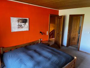 a bedroom with a bed and an orange wall at Ferienhaus Hochkönigblick in Leogang