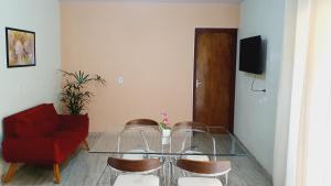 a living room with a glass table and a red couch at Casa Miríades in Hortolândia