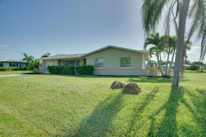 a house with a palm tree and two rocks in the yard at Waterfront Cape Coral Home Dock and Screened Porch in Cape Coral