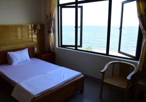 1 dormitorio con cama, ventana y silla en Thăng Long Hotel en Ðồng Hới