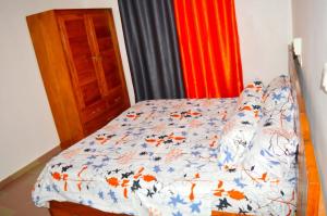 een slaapkamer met een bed met een blauw en oranje dekbed bij Résidence Lotus in Cotonou