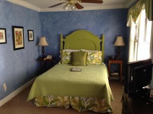 a bedroom with a green bed with blue walls at Mango Inn Bed and Breakfast in Lake Worth