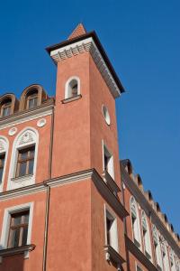 ein großes Backsteingebäude mit einem Uhrturm darauf in der Unterkunft Palazzo Rosso Old Town in Posen