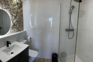 een witte badkamer met een douche en een wastafel bij Apartamentos playa Buendia in Suances