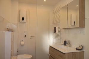 a white bathroom with a toilet and a sink at Living Concept Bogenhausen in Munich