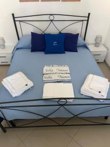 a blue bed with blue pillows and towels on it at Villa Imma in Torre Lapillo