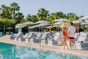 two people walking by the pool at a resort at Ivi Mare - Designed for Adults by Louis Hotels in Paphos