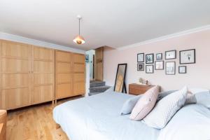 a bedroom with a white bed and wooden cabinets at Bright & spacious modern 2 bedroom apartment in London