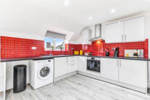 eine Küche mit weißen Geräten und roten Fliesen in der Unterkunft We Stay Baxter Gate 2 Bedroom Duplex Apartment in Loughborough