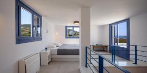 a white bedroom with a bed and two windows at White Dream Suites Antiparos in Antiparos