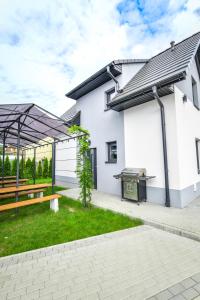 a white house with a picnic table and a grill at KempingZator in Zator