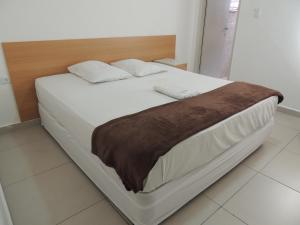 1 cama con sábanas blancas y manta marrón en Hotel Ourinhos - Centro de São Paulo - Próximo 25 de Março e Brás - By Up Hotel en São Paulo