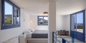 a white room with a bed and two windows at White Dream Suites Antiparos in Antiparos
