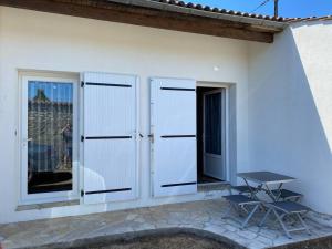 a patio with white doors and a picnic table at Studio duplex meublé avec place de parking in Surgères