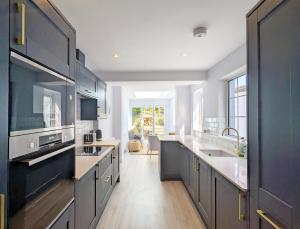 a large kitchen with black cabinets and a sink at Grace Cottage - Emsworth in Emsworth