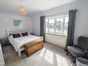 a bedroom with a bed and a chair and a window at Grace Cottage - Emsworth in Emsworth