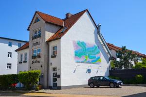 ein Auto, das vor einem Gebäude mit einem Gemälde parkt in der Unterkunft Hotel Nordlicht in Schwerin
