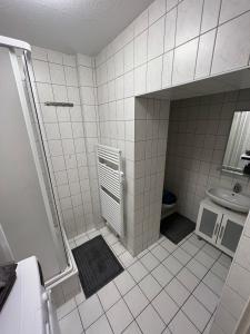 a white tiled bathroom with a shower and a sink at Elias 1 und 3 in Erfurt