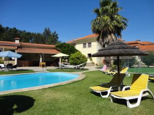 un gruppo di sedie e un ombrellone accanto alla piscina di Agroturismo Quinta Dom José a Braga