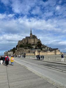a group of people walking on a sidewalk in front of a castle at Chez Tante Muguette proche Dinan in Le Hinglé