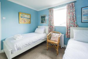 two beds in a blue room with a chair and a window at 8 Saxonfields in Snape