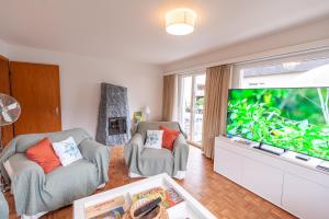 a living room with two chairs and a large screen tv at Sonnenkreisel Ferienhaus in Triesen