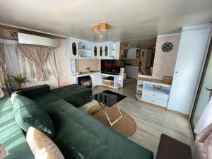 a living room with a green couch and a kitchen at Riverside Caravan in Valea Drăganului
