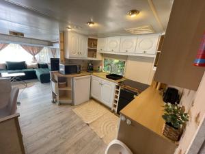 a kitchen with white cabinets and a living room at Riverside Caravan in Valea Drăganului