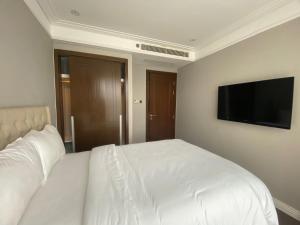 a bedroom with a white bed and a flat screen tv at Luxury Apartment in Da Nang