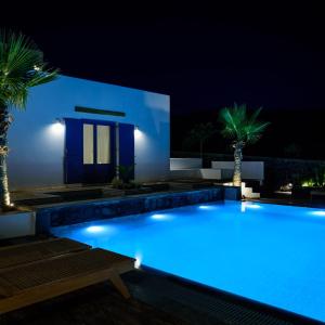 a swimming pool lit up at night with palm trees at White Dream Suites Antiparos in Antiparos