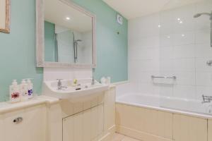 a white bathroom with a tub and a sink and a bath tubermott at Tiger Inn - Grace in Eastbourne