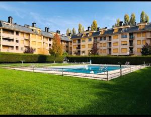 a large apartment complex with a swimming pool in the grass at Apartamento con encanto in Jaca
