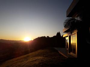 a house with the sun setting on the horizon at Villa Toscana - Vale dos Vinhedos in Bento Gonçalves