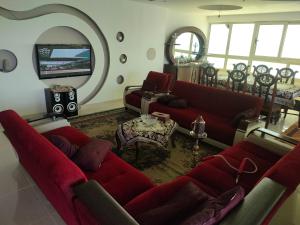 a living room with two red couches and a tv at شقه فاخره للايجار المفروش الابراهيميه على البحر in Alexandria