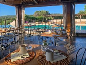 a restaurant with tables and chairs and a pool at Hôtel Maora Village in Bonifacio