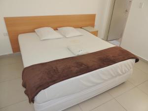 duże łóżko z białą pościelą i drewnianym zagłówkiem w obiekcie Hotel Ourinhos - Centro de São Paulo - Próximo 25 de Março e Brás - By Up Hotel w São Paulo