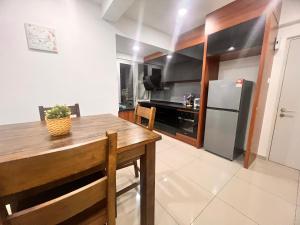 a kitchen with a wooden table and a refrigerator at PANGSAPURI MIDAS in Johor Bahru