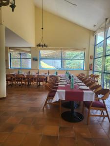 una sala da pranzo con tavoli, sedie e finestre di COMPLEXO TURISTICO PONTE MOURULLE 