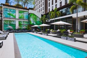 a swimming pool with chairs and umbrellas next to a building at The BRIX Autograph Collection in Port-of-Spain