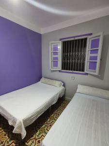 twee bedden in een kleine kamer met een raam bij فندق آل الشيخ أحمد in Targuist