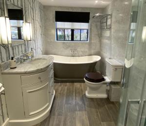 uma casa de banho com uma banheira, um WC e um lavatório. em Luxury Barn conversion, 3 bed, 3 bath with hot-tub em Bedford