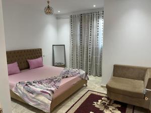1 dormitorio con 1 cama y 1 silla en Maison Eline en Harqalah
