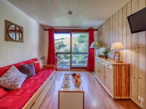 sala de estar con sofá rojo y ventana en Apartment Pegase Phenix-6, en Le Corbier