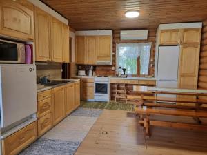 a kitchen with wooden cabinets and white appliances at Holiday Home Saarenpää by Interhome in Koivisto
