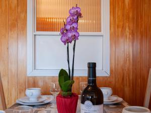 a table with a bottle of wine and a purple orchid at Apartment Christiania 2 L3 by Interhome in Nendaz +28 photos