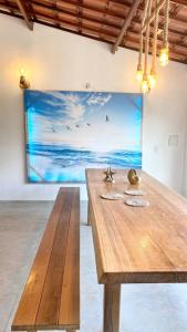 einen Holztisch in einem Zimmer mit einem Gemälde an der Wand in der Unterkunft Villa do Nino in Canoa Quebrada