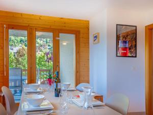 uma sala de jantar com uma mesa longa e cadeiras brancas em Apartment Les Chouettes 11 by Interhome em Nendaz