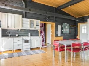 a kitchen with white cabinets and a table with red chairs at Holiday Home Aamunkoi by Interhome in Pyhäsalmi +25 photos