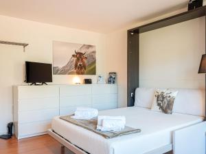 um quarto com uma cama branca e uma tv em Studio Bouleaux K4 by Interhome em Nendaz