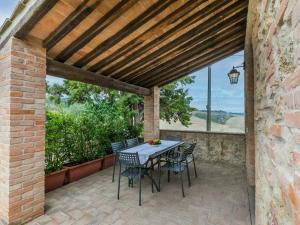 eine Terrasse mit einem Tisch und Stühlen unter einer Holzdecke in der Unterkunft Holiday Home Villa Caggio-4 by Interhome in Volterra